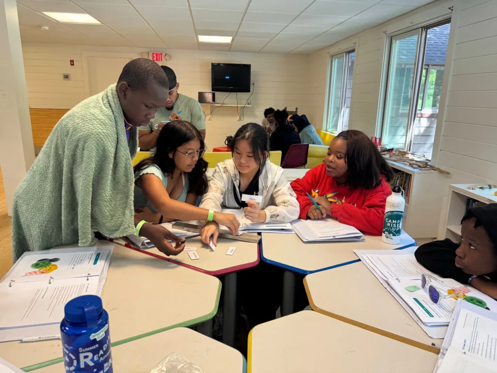 Teens working together at a table during a Camp Rise Up class