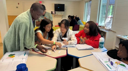 Teens working together at a table during a Camp Rise Up class