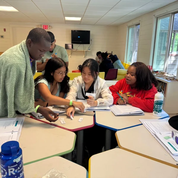Teens working together at a table during a Camp Rise Up class